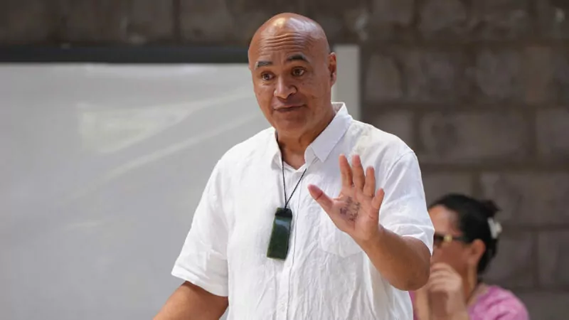 Māori Samoan man in white shirt and pound presenting standing and talking