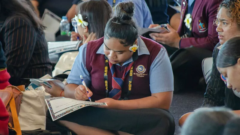 Young woman seated on the floor writing in a notebook