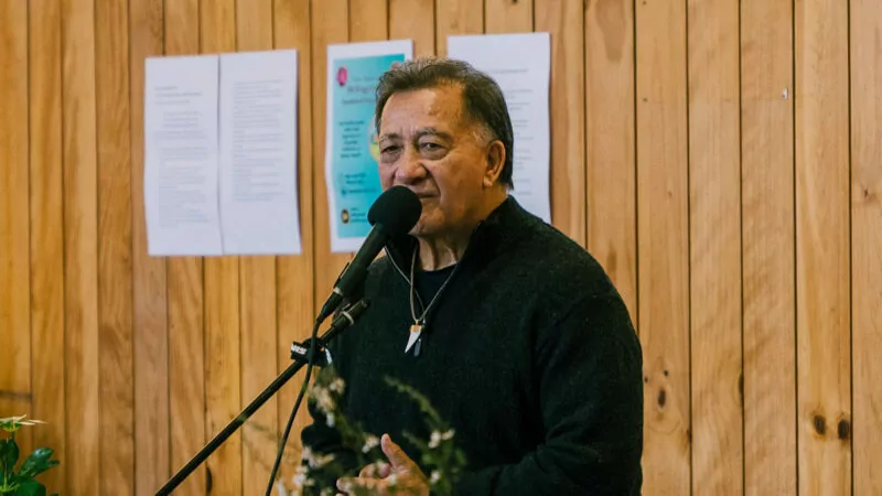 Older man speaking into a stand microphone