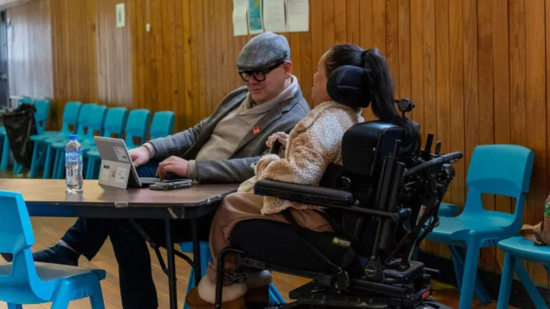 Older man in a hat talks with a young woman in a wheelchair