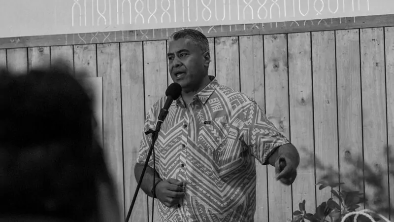 Man in a Pacific shirt standing and speaking into a microphone
