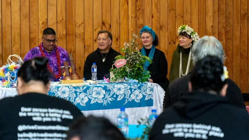 A group of people seated at a table dressed in colourful Pacific attire